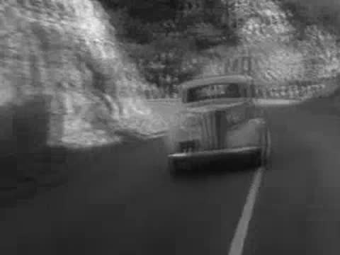 A vintage car driving on a winding mountain road.
