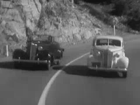 Car dashboard speedometer and a vintage car driving on a road.