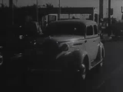Two vintage cars driving on a winding mountain road.