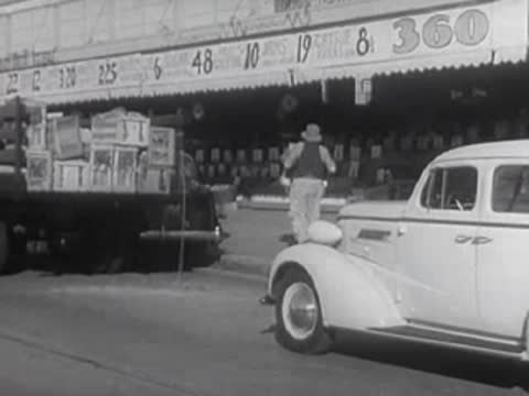 A man working near a truck parked outside a storefront.