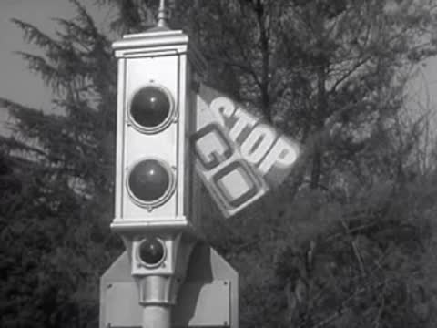A traffic signal swings its mechanical arms reading STOP and GO.
