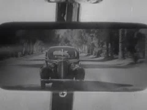 View in the rear-view mirror of a car being followed on a road.
