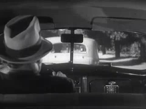 A driver is seen from the back seat following another vehicle.