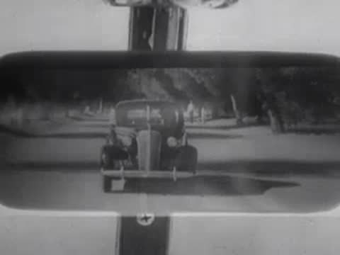 A rear-view mirror shows another vehicle following closely behind.