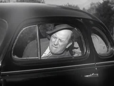 A driver looks out the window of a vintage car.