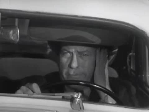A driver behind the steering wheel reacts with expression inside a car.