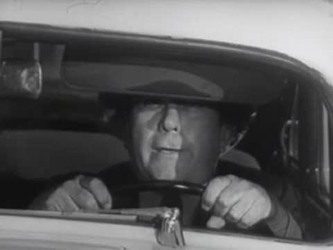 A driver looks straight ahead while driving a car at night.
