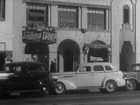 A white sedan parked on a street in front of a commercial building.