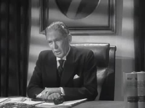 A man sits behind a desk looking down thoughtfully in an office.