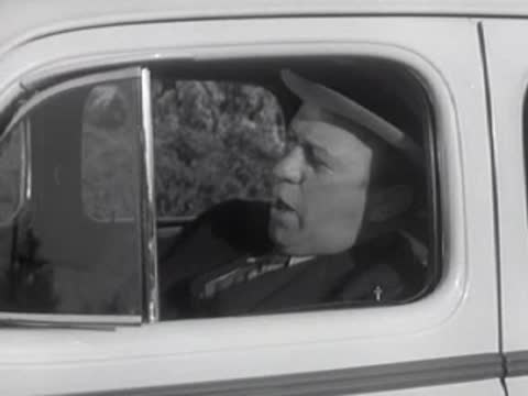 Man in fedora and suit looking sideways out car window.