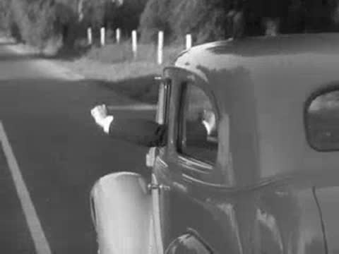 Arm gesturing out car window while driving down road.