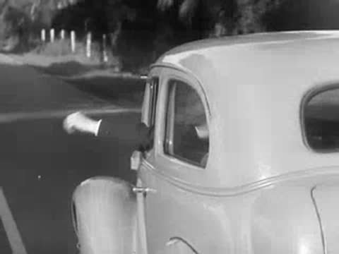 Car driving down road with hand signaling out window.