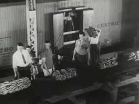 men unloading crates from truck or container onto a platform in warehouse