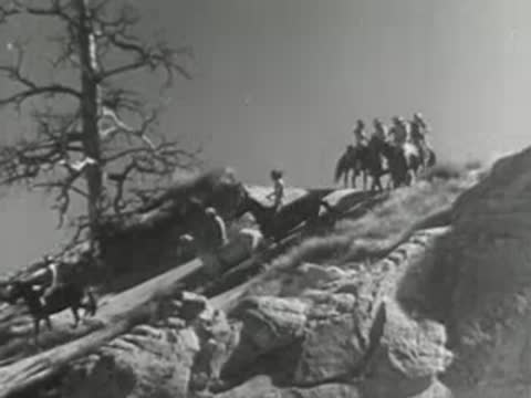 People riding horses along a steep rocky mountain trail