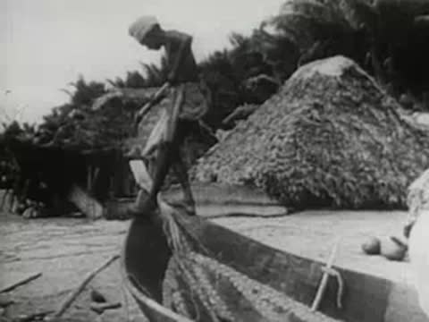 man in a small boat packing fishing nets on a beach
