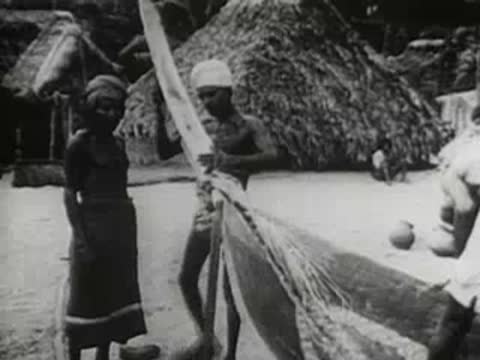 two people holding up a large fishing net on a sandy beach