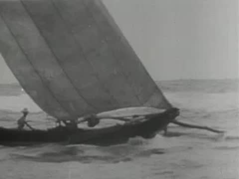 close-up of a small outrigger sailboat cutting through ocean waves