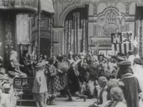 a crowd of people in historical costumes gathered in an ornate hall