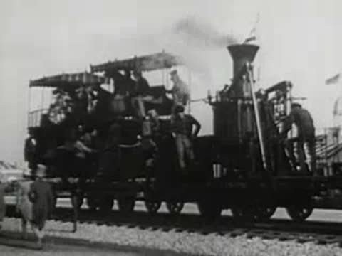 an old steam locomotive with passengers riding on top standing on tracks