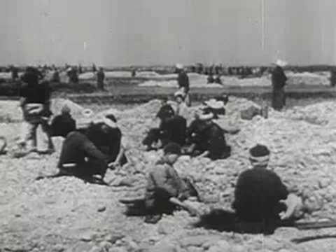 People breaking stones outdoors in a vast open landscape
