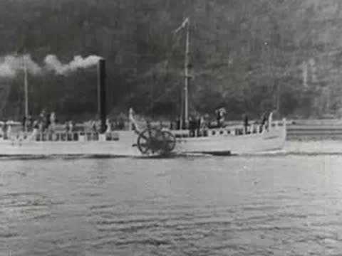 paddle steamer boat traveling along a calm waterway with trees along the bank