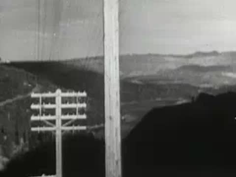 Telegraph pole with multiple crossbars and wires against cloudy sky, historical communication infrastructure