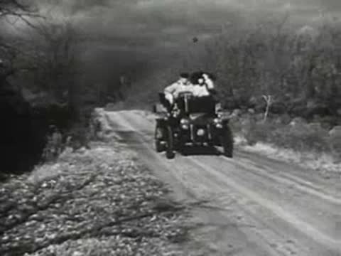 Early vintage automobile driving forward on a dirt road, historical transport