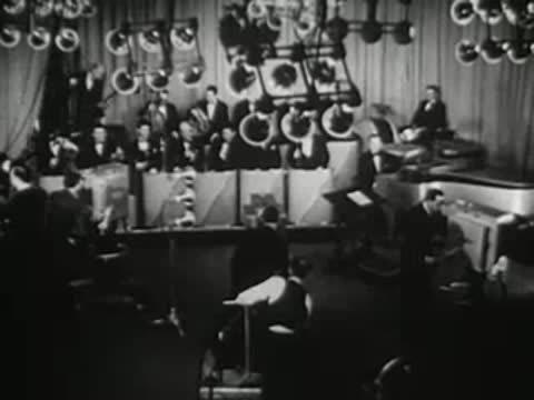 Orchestra playing in a studio with microphones and stage lighting, musical broadcast performance