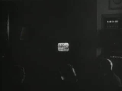 Technician operating a television broadcast camera in a studio, early television production
