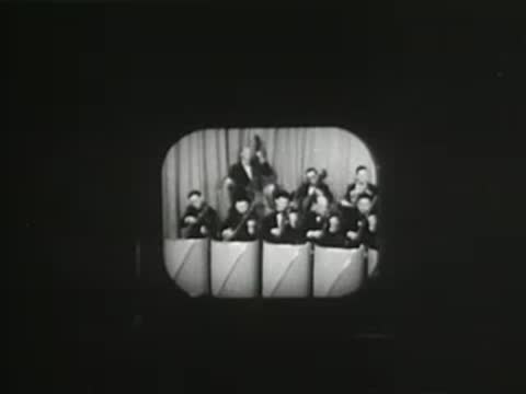 Studio monitor displaying a live musical performance on a small screen, early television technology