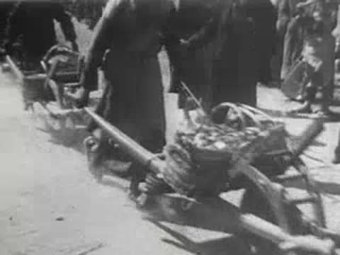 People moving wheelbarrows across a rocky outdoor work area
