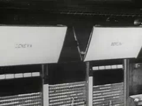 Close-up of telephone switchboard panels with destination labels and cables, 1940s.