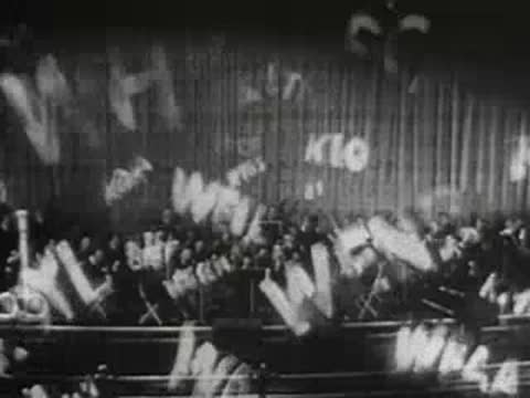Radio station call letters graphic superimposed over a live orchestra performance.