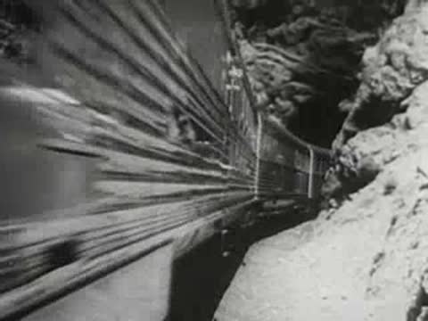 Streamlined passenger train entering a tunnel in a rocky mountain area, 1940s.