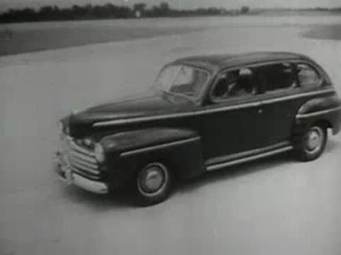 Streamlined train traveling through a canyon followed by a vintage car on a road.