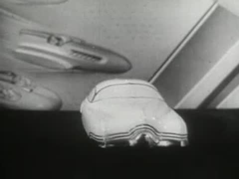 Model toy car and futuristic vehicle design against a graphic background, 1940s.