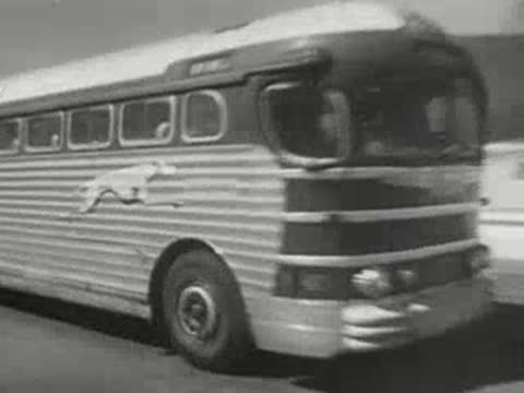 greyhound bus driving along a highway in a landscape with hills