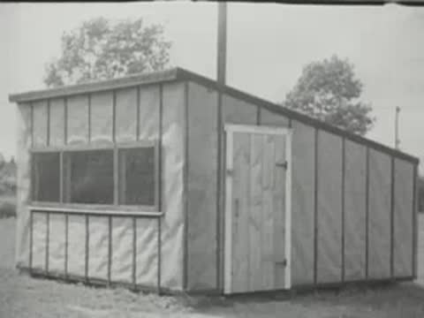 Exterior view of a small wooden poultry house with windows and door