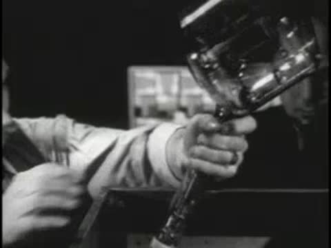 Worker handling a glass cathode-ray tube in a lab.