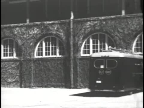 Two RCA mobile television vans parked in front of an arched brick building.