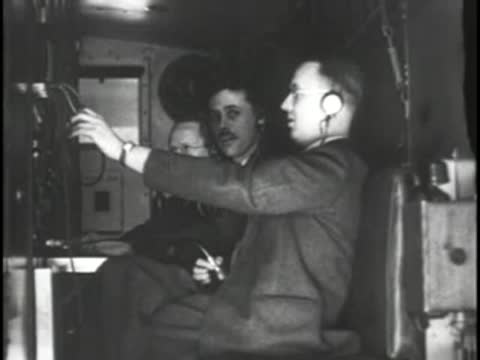 Two technicians wearing headsets sit inside a mobile broadcast van.