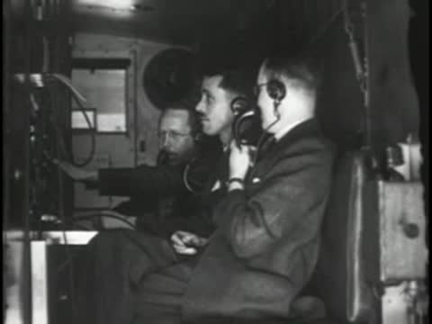 Men wearing headphones sitting inside a control room or production vehicle