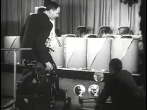 Studio cameraman operating a vintage television camera in front of stage setup