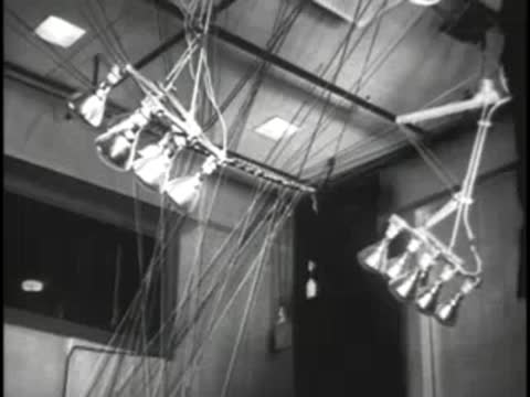 Technician operating a complex patch panel with many hanging audio cables
