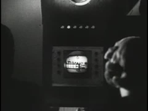Technician looking at a small vintage television monitor in a control room