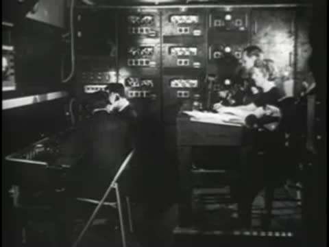 Technicians working at a control console with multiple electronic display screens