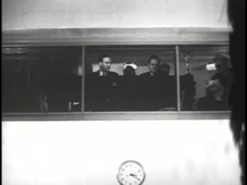 Control room view through a glass window with a wall clock below
