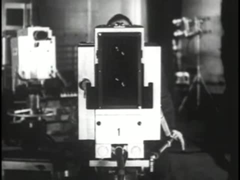 Large vintage television camera facing forward with visible lenses on stage