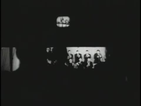 Control room monitor displaying an orchestra performance on television.