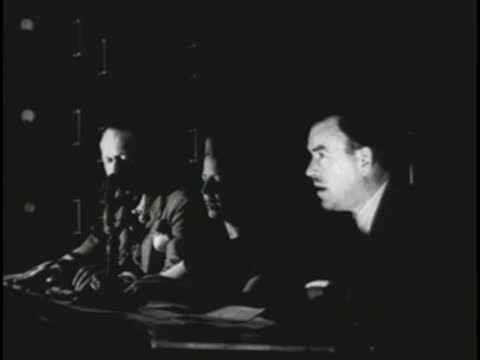 Audio engineers monitoring a live broadcast from a dark control room.